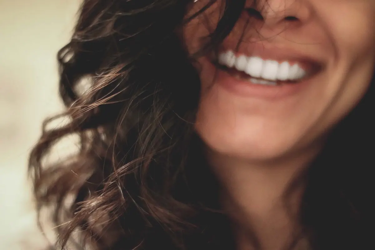 Close-up of a woman laughing, cropped above the eyes